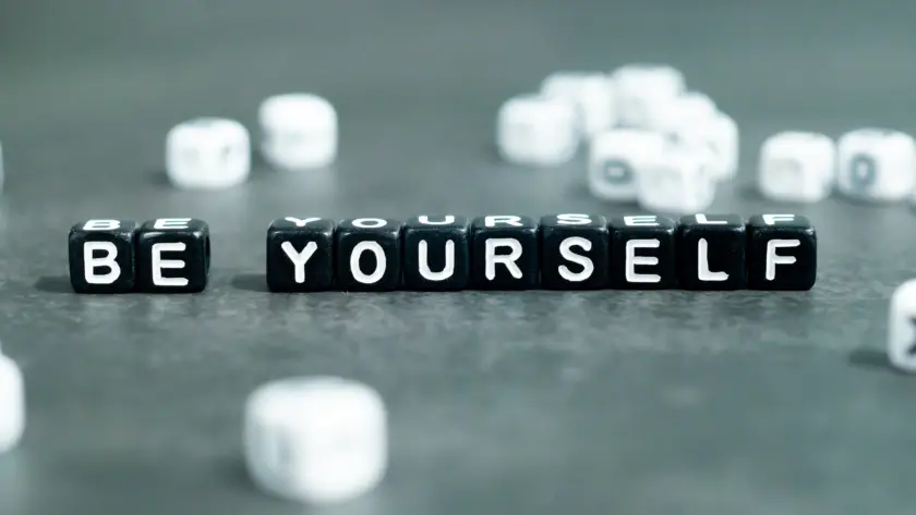 Black letter blocks spelling BE YOURSELF with blurred blocks in background