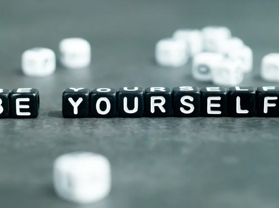 Black letter blocks spelling BE YOURSELF with blurred blocks in background